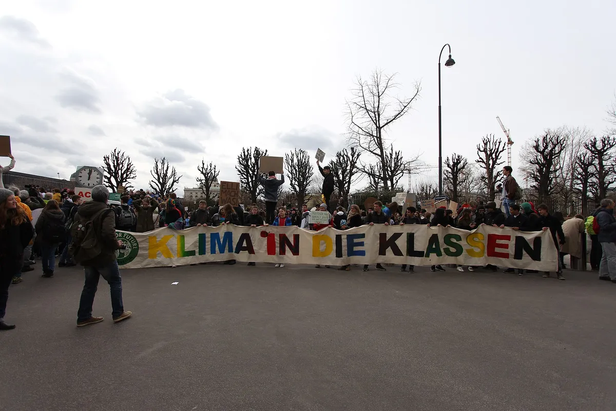Jugendliche tragen ein langes Transparent mit der Aufschrift Klima in die Klassen über die Ringstraße